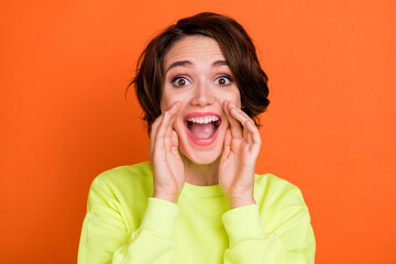 Portrait of attractive amazed cheerful girl saying great news ad advert isolated over vibrant orange color background