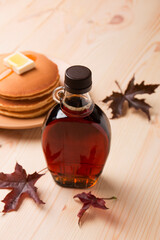 Beautiful Canadian maple syrup in a bottle on a light wooden background. Pancakes with syrup or honey.
