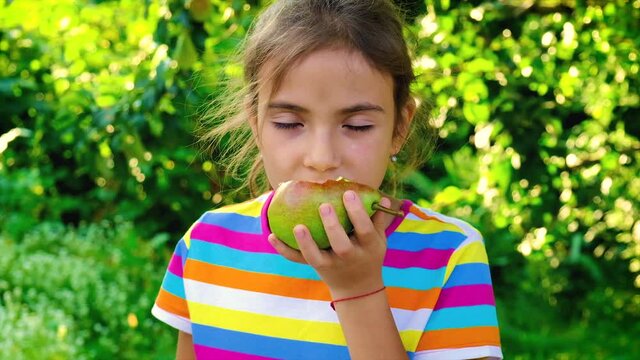 The child eats a pear in the garden. Selective focus.