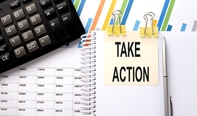TAKE ACTION text, written on a sticker with calculator,pen on the chart background.