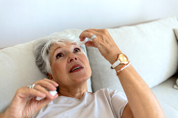 A sick old woman suffering from irritated eye, optical symptoms. A senior woman applying eye drop...