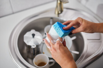 Unrecognizable woman housewife washing dishes in the kitchen at home over sink, lifestyle, House equipment.
