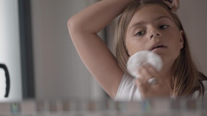 young girl doing facial cleansing in front of a mirror