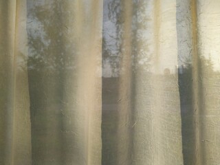 white curtains on the window and the light of the sun at sunset.