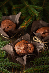 Delicious chocolate muffins on dark wooden background among fir branches, Merry Christmas and Happy New Year
