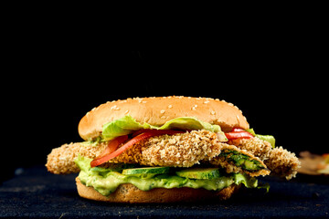 Vegetarian burger with pesto sauce, cucumber, tomatoes and asparagus in batter on a dark background.. Close up , selective focus