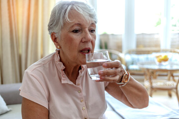 Cropped shot of a woman drink pure clean mineral water from glass, for body refreshment and good health. Mature grandmother feel thirsty enjoy clean still aqua for hydration, healthy lifestyle concept