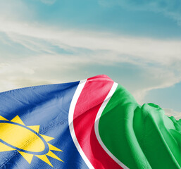 Namibia national flag cloth fabric waving on the sky with beautiful sun light - Image