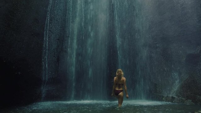 beautiful woman under waterfall in cave wearing bikini enjoying refreshing water splashing having fun carefree vacation 4k