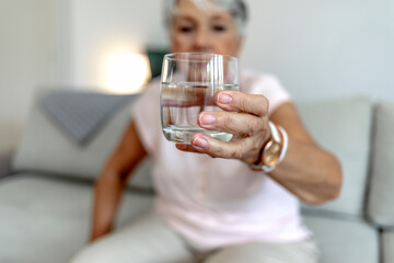 Smiling, beautiful old lady drinking a glass of water. Close up aged woman hold glass drink still...