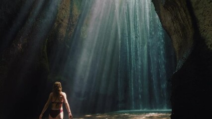 happy woman dancing in waterfall cave wearing bikini having fun enjoying freedom with arms raised feeling carefree tropical vacation 4k