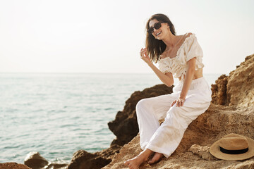 Fototapeta na wymiar Woman traveler sitting near sea on cliff injoying view of sea and nature