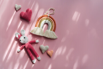 Rainbow hearts and knitted bunny on pink background. Cute decoration and accessories for baby and children's room. Flat lay, top view