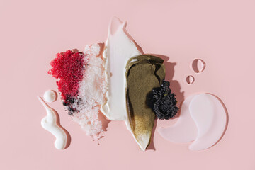 Composition of various cosmetic mask, creams, serum, scrub and lotion smear on a pink background....