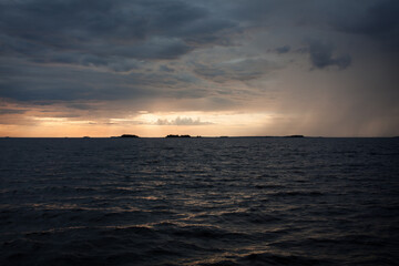 Obraz premium Sunset over the sea, with waves, stormy clouds and rain.