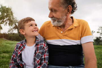 Cute little boy and grandfather spending time together in park