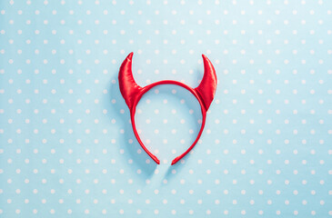 Red devil horns on a headband hoop. Halloween texture background