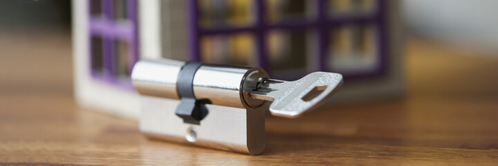 Keyhole with key lying near wooden toy house closeup