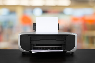 Compact laser printer on black desk against blurred background