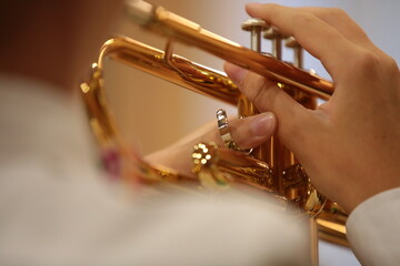 Musical instrument in hand with finger on key of trumpet valve. Music background image close-up