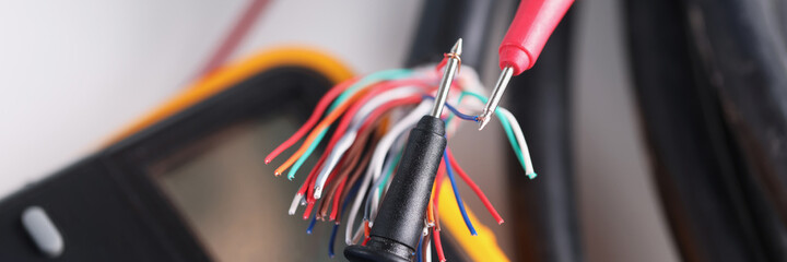 Two multimeter probes checking quality of network wiring closeup