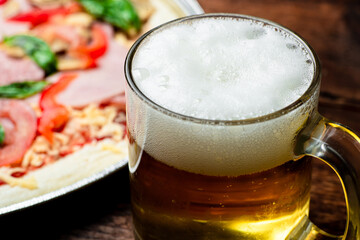 Glass of beer close up on pizza background.