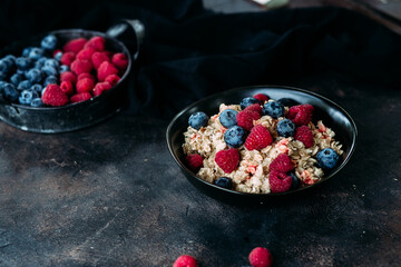 Oatmeal with raspberries and blueberries in a black plate