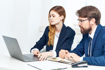 Fototapeta premium business man and woman chatting in the office in front of a laptop professionals