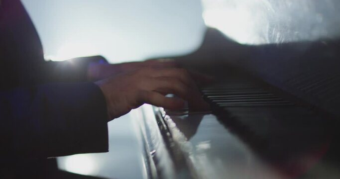 4K Footage of male hands playing grand piano . Man touches fingers on keys . Pianist plays in beautiful grand piano on stage in concert . Close up . Shot on ARRI ALEXA movie camera in slow motion .