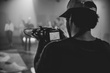 Grayscale shot of cameraman holding camera on a studio