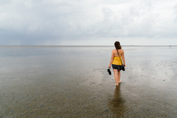 Young woman walking alone in a calm and tranquil beach at low tide