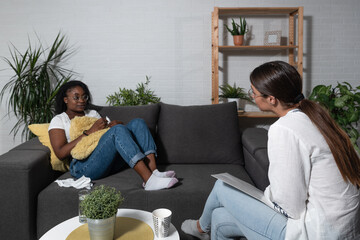 Young black African woman sitting with a psychotherapist in the office has a conversation therapy...