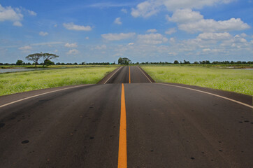 Naklejka premium Long road though the field on the hill