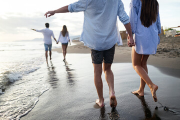 Fototapeta premium Group of happy friends having fun walking down the beach at sunset