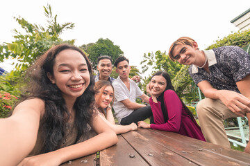 Six southeast asian friends taking a selfie on a bench outdoors.Cheerful and upbeat mood. Gen Z...