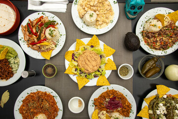 Set of Mexican food dishes with fajitas, peppers, corn chips, chicken tinga stew, pumpkin flower chicken, nopales with cheese, ripe avocado and jalapeños