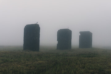 Mysterious abandoned industrial pillars, standing on moorland. On a spooky, foggy day.