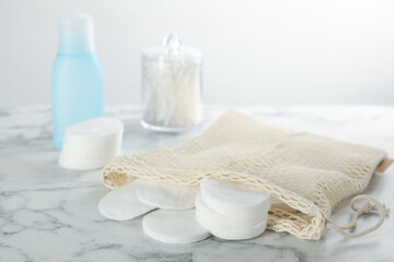 Cotton pads and makeup removal product on white marble table