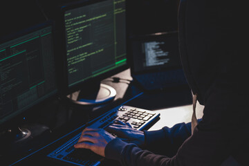 Hacker in front of computer. view from shoulder. hacker in the hood typing text