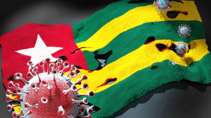 Covid in Togo - coronavirus attacking a national flag of Togo as a symbol of a fight and struggle with the virus pandemic in this country, 3d illustration