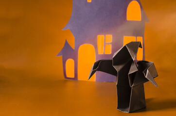 The figure of a dark ghost against the background of a black house with red windows. The concept of a haunted house made of paper