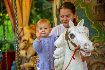 Obraz na płótnie Canvas Cute baby girl with mother on the horse of old retro carousel, Prague, Czech republic 