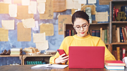 書斎でスマホとPCを使う女性