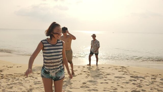 4K Group of Happy Asian man and woman friends running and playing together on tropical beach in sunny day. Male and female friendship enjoy and having fun outdoor lifestyle activity on summer vacation