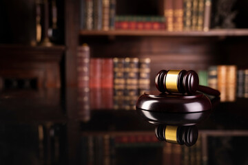 Law theme. Judge chamber. Gavel on brown desk. Collection of legal books in the bookshelf.