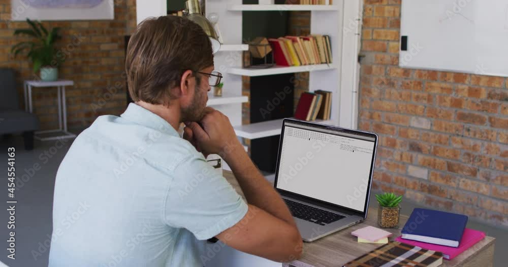 Poster caucasian man sitting at desk watching coding data processing on laptop screen
