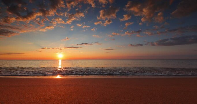 Ocean sunrise with dramatic sky clouds and golden sun rays over island beach