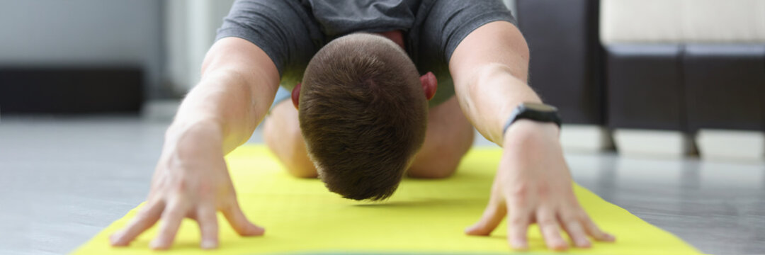 Young man is doing exercises to stretch his back muscles
