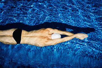 professional swimmer floating under water in pool
