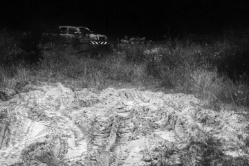 tire prints in sand quarry near forest pick up truck in distance, abstract black and white pattern background